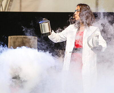 Science-Festival-Darbietung mit Forscherin im Arbeitskittel, Wasserkocher und viel Dampf