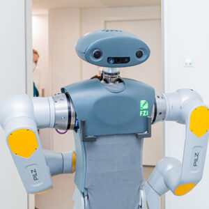 Serviceroboter HoLLiE in einem Patientenzimmer im Städtischen Klinikum Karlsruhe, Pflegekraft im Hintergrund