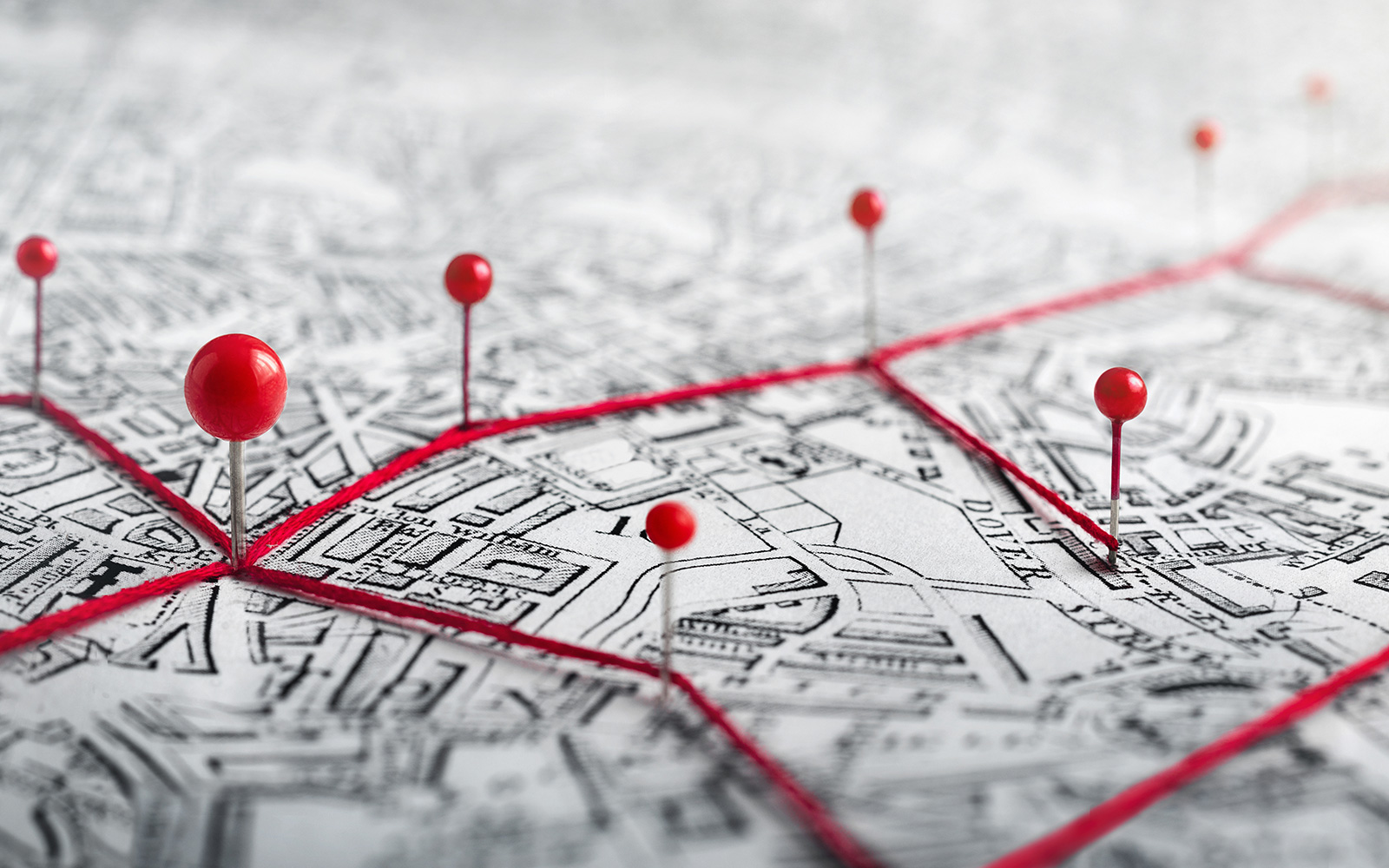 Stadtplan mit roten Stecknadeln und roten Fäden