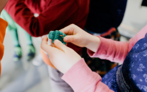 Kinderhände halten eine 3D-gedruckte Figur des FZI-Roboters HoLLiE
